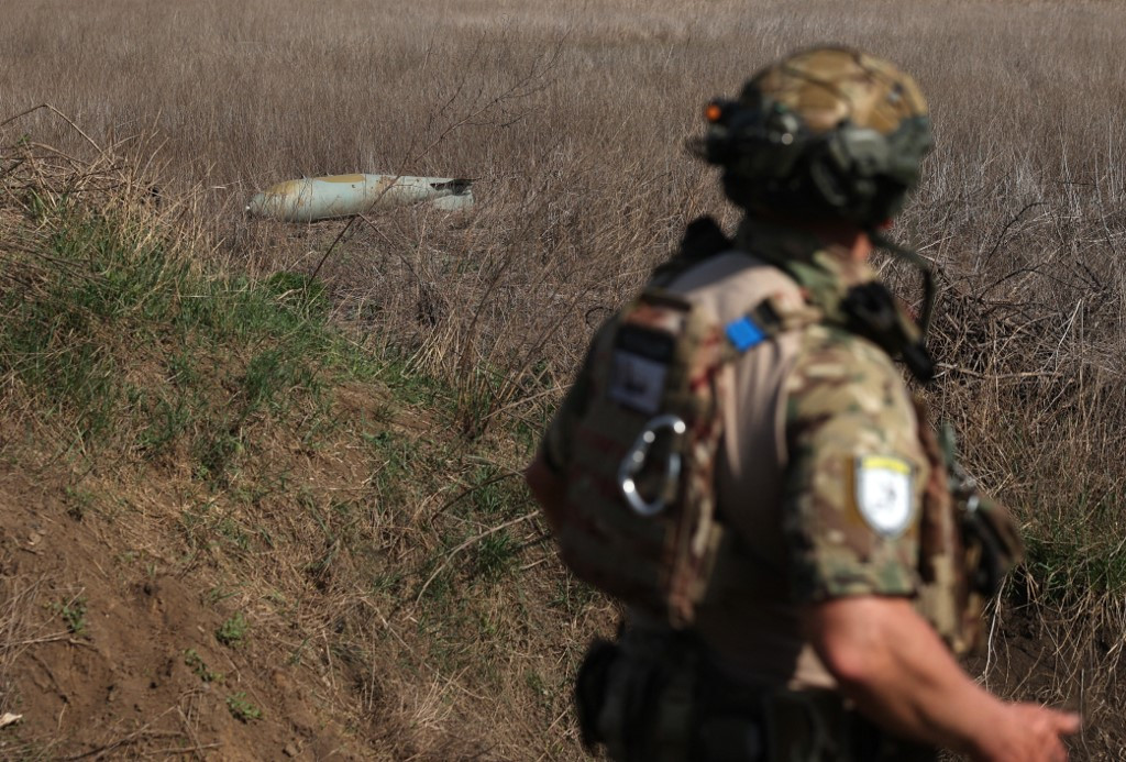 Un soldat passe devant une bombe aérienne russe FAB-500 non explosée dans un champ près du village d’Ocheretyne, non loin de la ville d’Avdiivka, dans la région de Donetsk, le 15 avril 2024, dans le cadre de l’invasion russe en Ukraine.